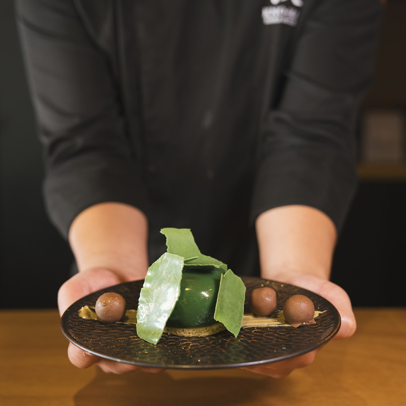 Detail of a signature dessert at Kno-Ma, paying tribute to Patek Philippe's technical precision during the itinerant collection event.