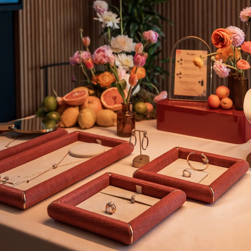Selección de joyas Pomellato expuestas en bandejas de terciopelo, rodeadas de flores y cítricos inspirados en el Mediterráneo durante una presentación exclusiva.